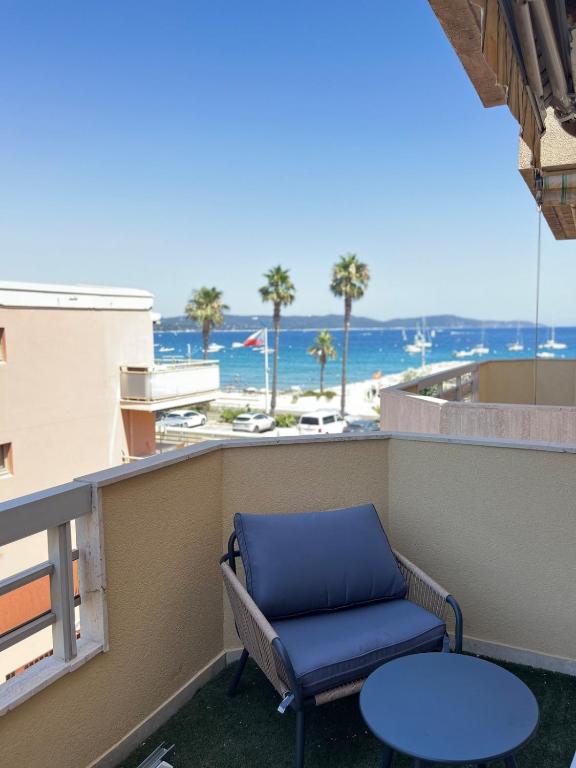 une chaise bleue sur un balcon avec vue sur la plage dans l'établissement 50m de la MER, à Cavalaire-sur-Mer
