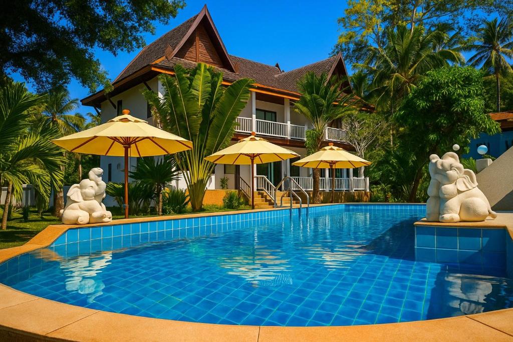 a swimming pool in front of a house with umbrellas at Villa Giacomelli Samui in Amphoe Koh Samui