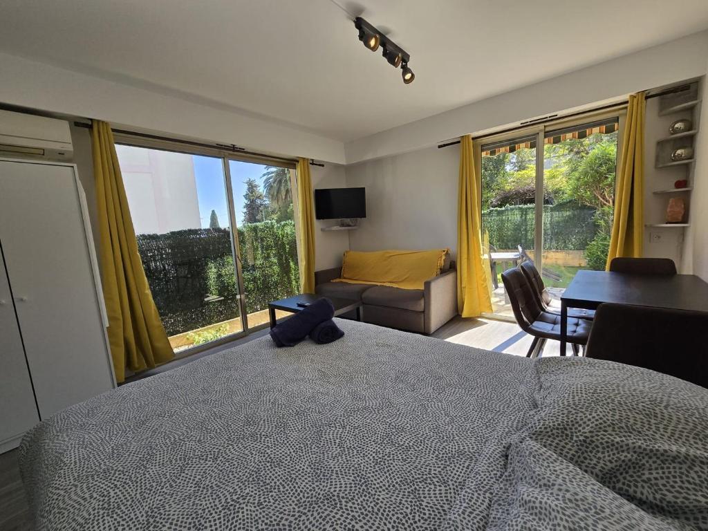une chambre avec un grand lit et un salon dans l'établissement Charmant Studio avec jardin - Calme - Proche plage, à Cagnes-sur-Mer