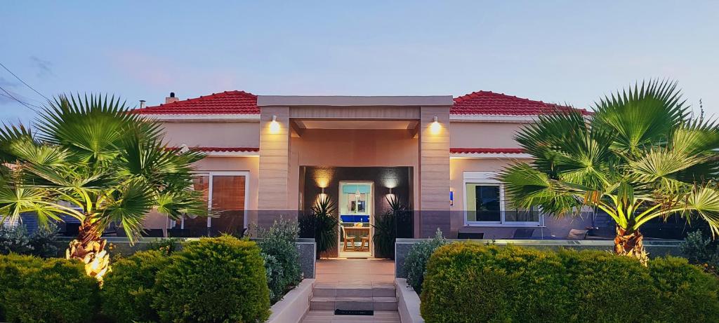 a house with palm trees in front of it at Luxury Villa Eva-Mari with jacuzzi, 50m from the beach in Stalos