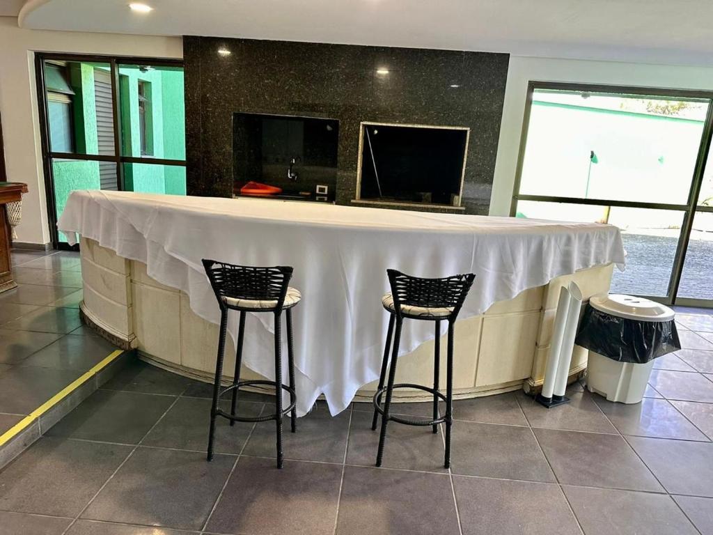 a bar with a white table and two stools at Espaço Life - Eventos in Curitiba