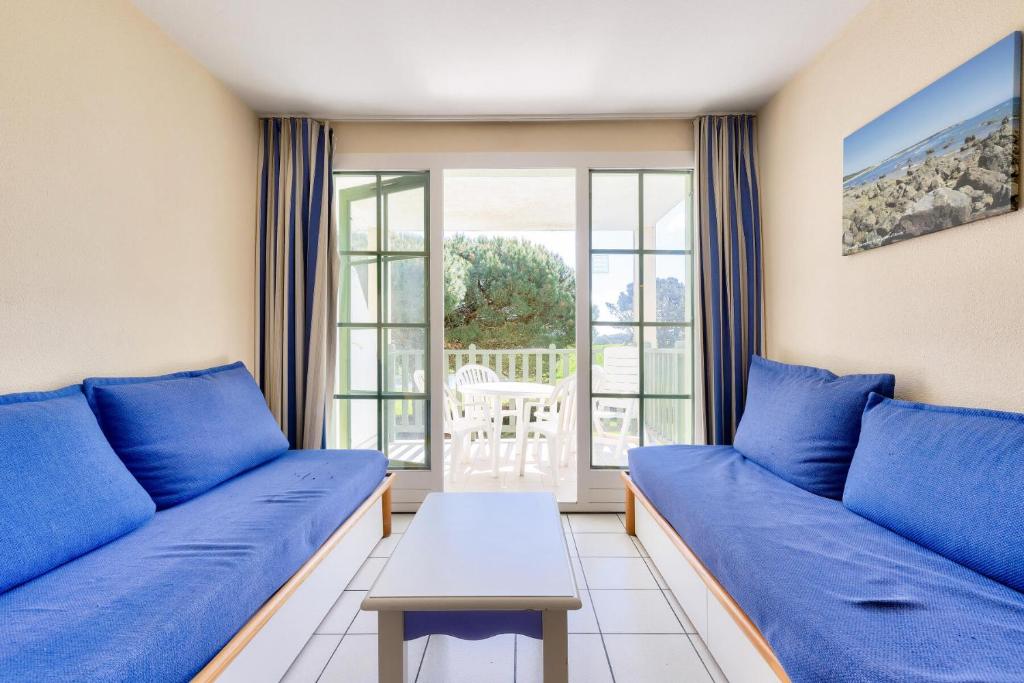 un salon avec des canapés bleus et une table dans l'établissement Résidence Port Bourgenay - maeva Home - 2 Pièces 5 Personnes Sélection MAE-2093, à Talmont-Saint-Hilaire