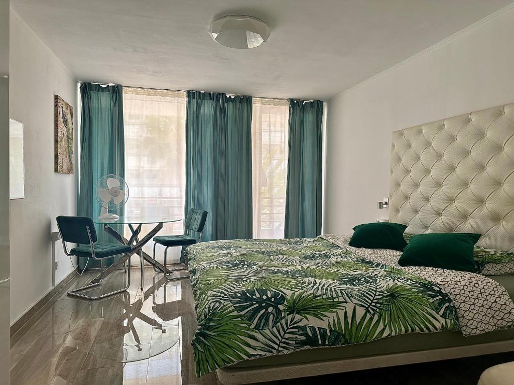 una camera da letto con un letto, un tavolo e tende verdi di Olympia 424 a Playa de las Americas