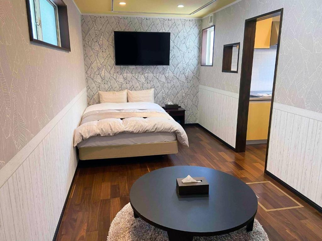 ein Schlafzimmer mit einem Bett, einem Tisch und einem Fernseher in der Unterkunft Pension Alhambra - Vacation STAY 15537v in Manazuru