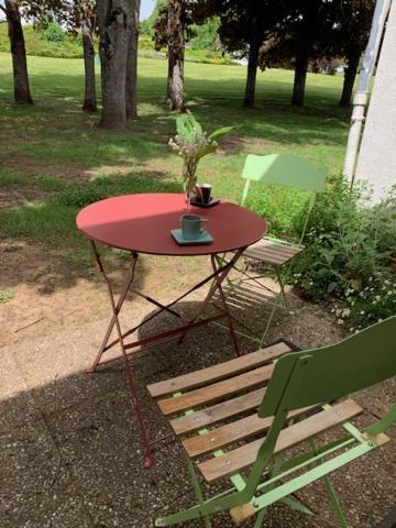 a red table with a plant on it next to a chair at ~ le Terracotta ~ Studio 1/4 pers / Futuroscope in Chasseneuil-du-Poitou