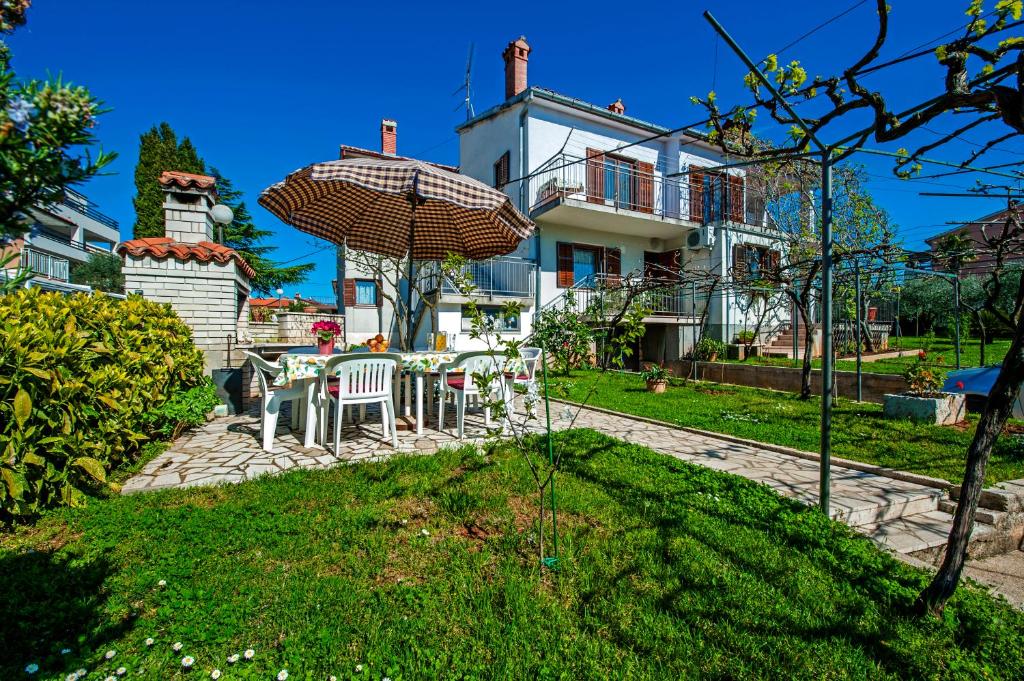 uma casa com uma mesa e cadeiras e um guarda-sol em Apartments Severina em Rovinj
