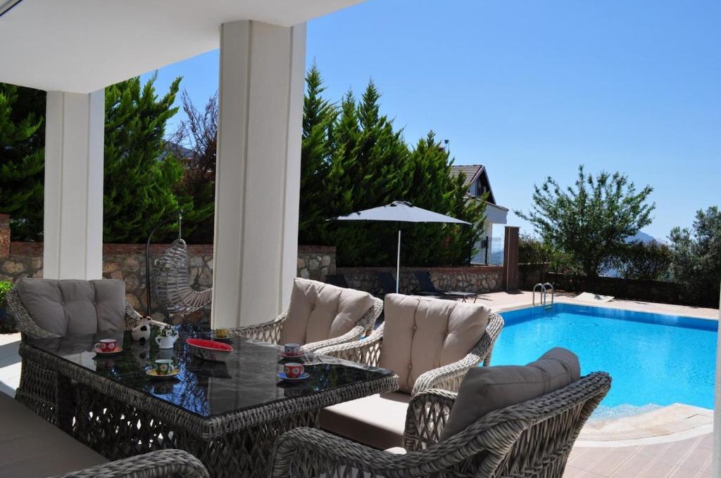 Un patio con mesa y sillas junto a una piscina. en Villavoyn, en Fethiye