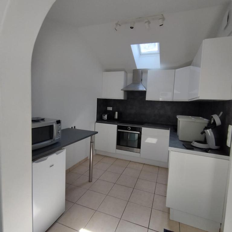 une cuisine blanche avec des armoires blanches et un évier dans l'établissement Petite maison bord de mer, à Langrune-sur-Mer