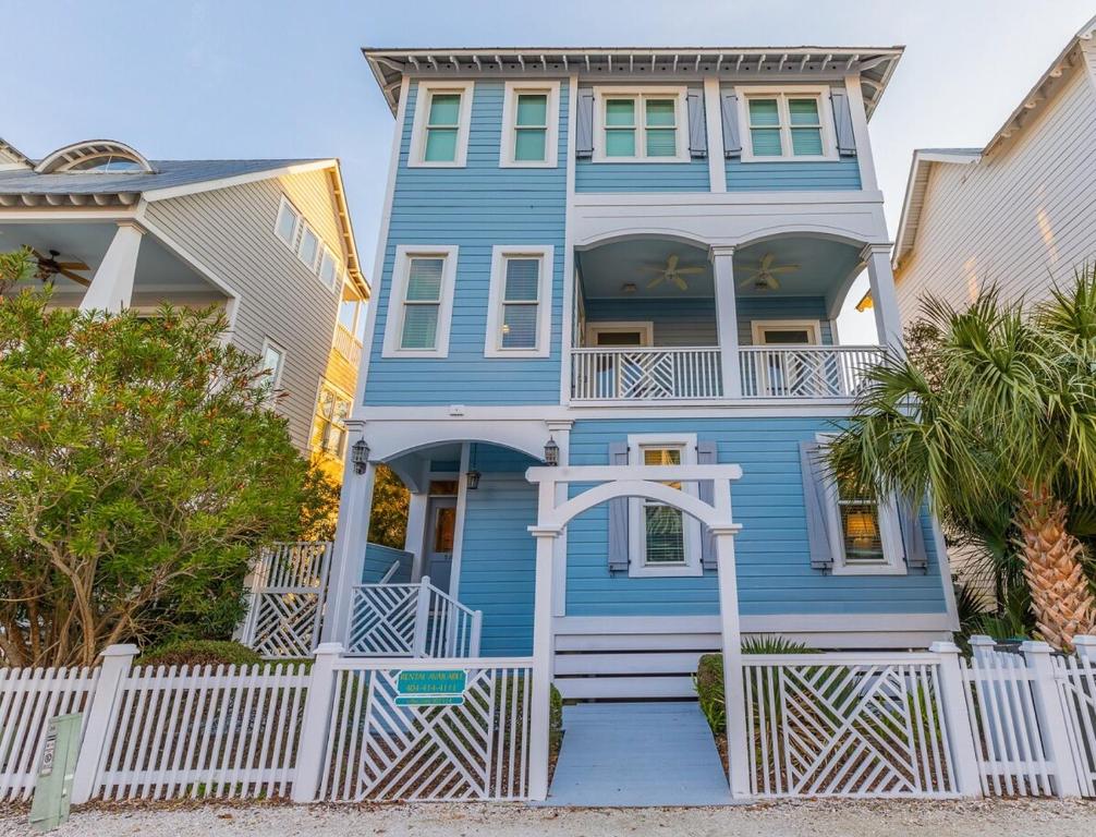 una casa blu con una recinzione bianca davanti di Centennial Coast Cottage - with Heated pool a Saint Simons Island
