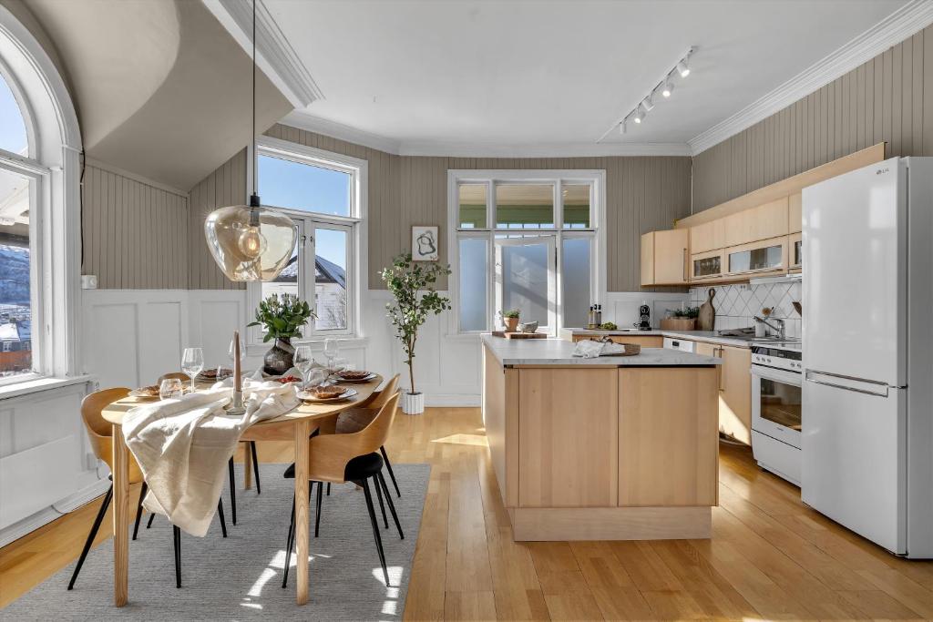 une cuisine avec une table et un réfrigérateur blanc dans l'établissement Lovely city center apartment with amazing views and free parking!, à Tromsø