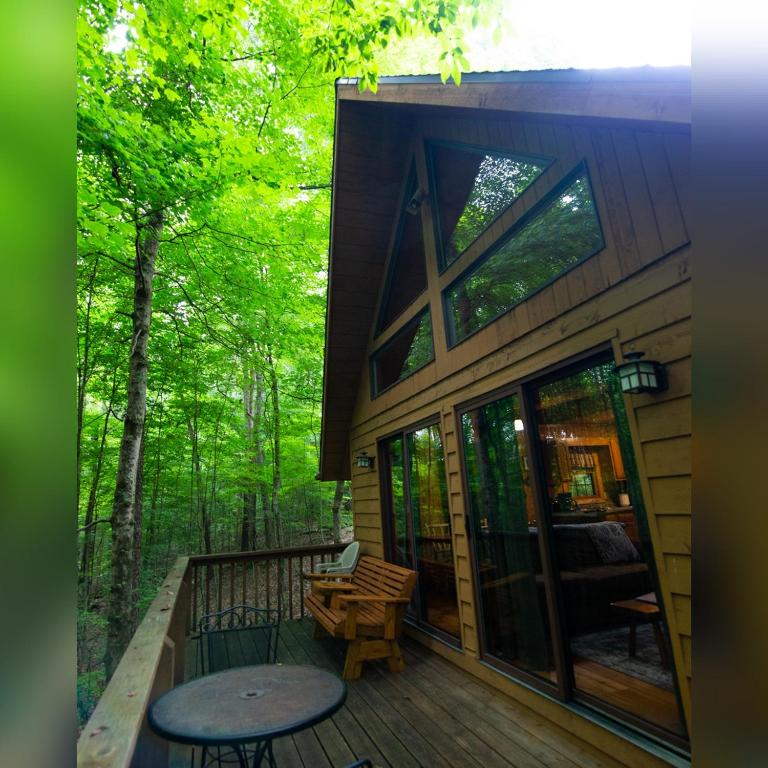 a house with a deck with a table and a bench at Elk - by The Chalets in South Bloomingville