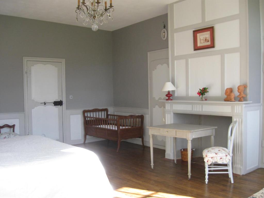 a bedroom with a bed and a table and a chair at Chambres d'hôtes de charme Le Pradel in Monceaux-sur-Dordogne