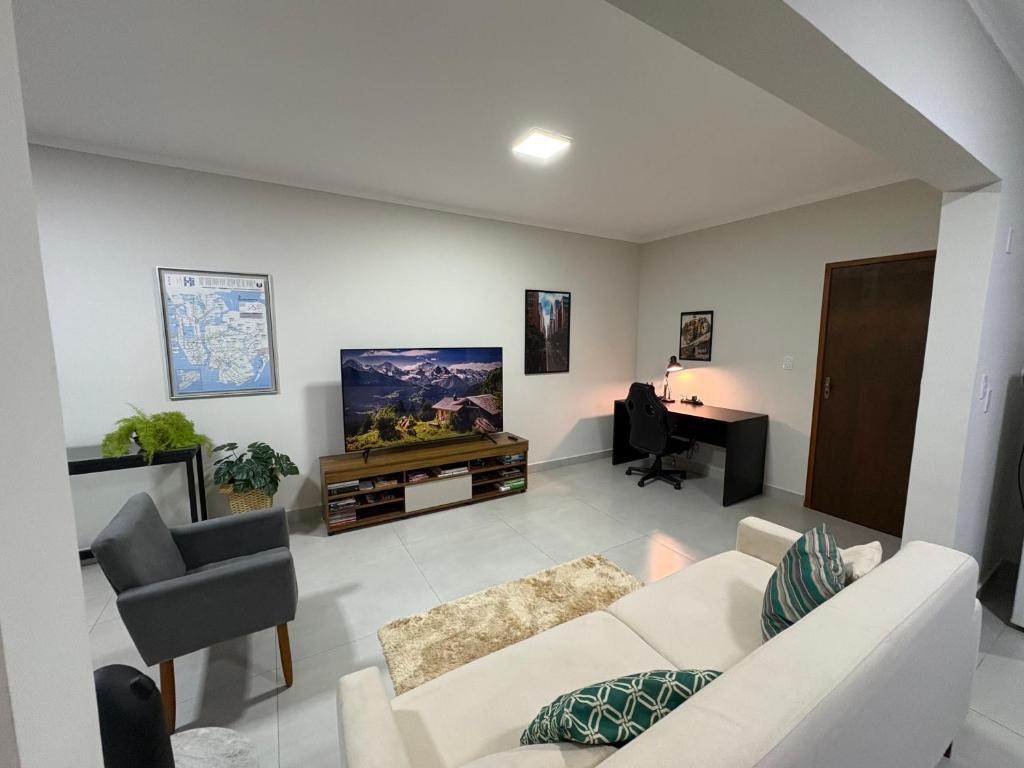 a living room with a white couch and a piano at Apartamento no centro de São Lourenço e a 750 metros do parque in São Lourenço