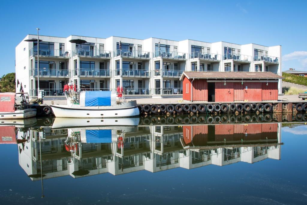 a apartment building with a boat in the water at Beautiful harbor view apartment in Hvide Sande