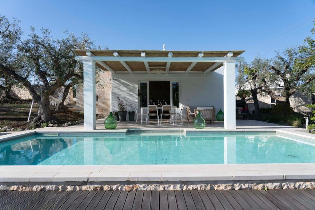 a swimming pool with a pergola next to a house at Trullo Zaira in Alberobello