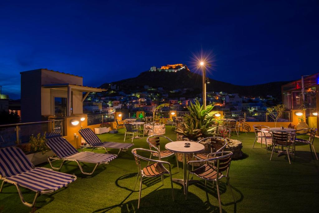 a patio with tables and chairs on a roof at night at Elefteria Hotel in Agia Marina