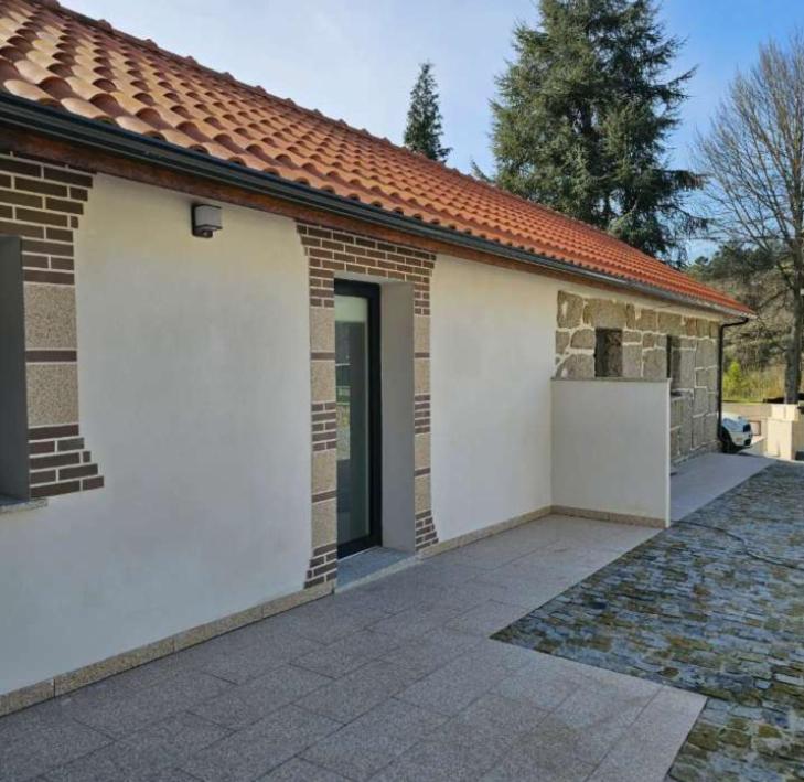 a small brick house with a door and a driveway at Alojamentos pinheiros in Amarante