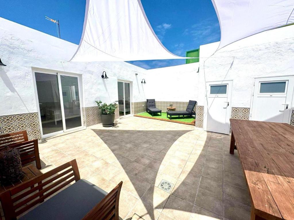 Un patio con bancos y mesas y un edificio blanco. en Casa Caladero, en El Golfo