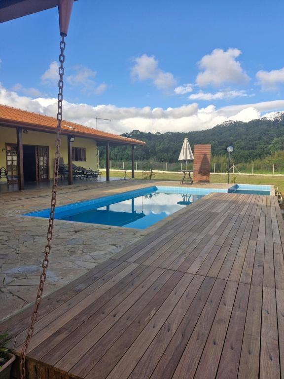 a porch with a wooden deck and a swimming pool at Recanto Girassol em São Roque - Rota do Vinho in São Roque