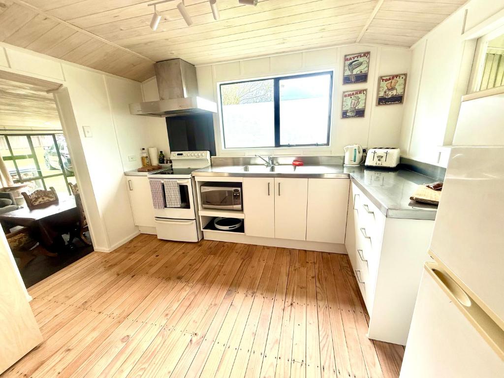a kitchen with white cabinets and a wooden floor at Good times at the Lake in Mangakino