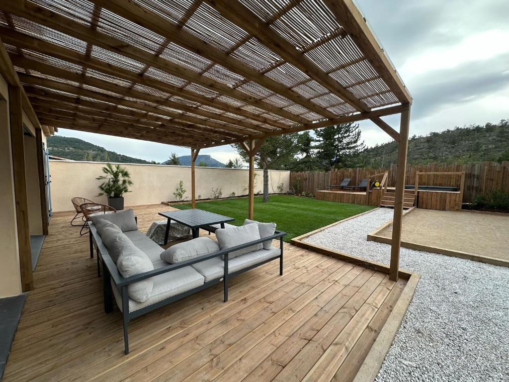 a patio with a couch under a wooden pergola at La Maison Myrtille in Castellane