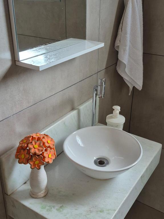 a bathroom with a sink and a flower vase on a counter at Casinha Verde in Passa Quatro
