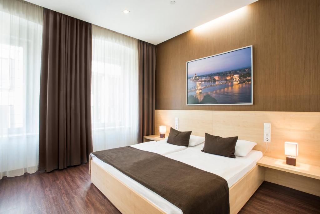 a bedroom with a large bed and a large window at Promenade City Hotel in Budapest