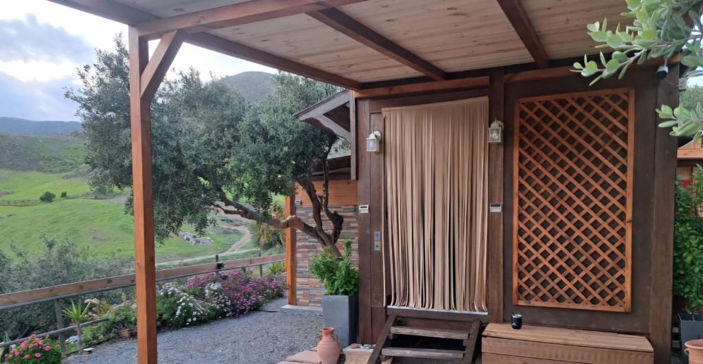 a wooden pergola with a view of a field at Wooden House at the Mountain-private in Paránimfoi
