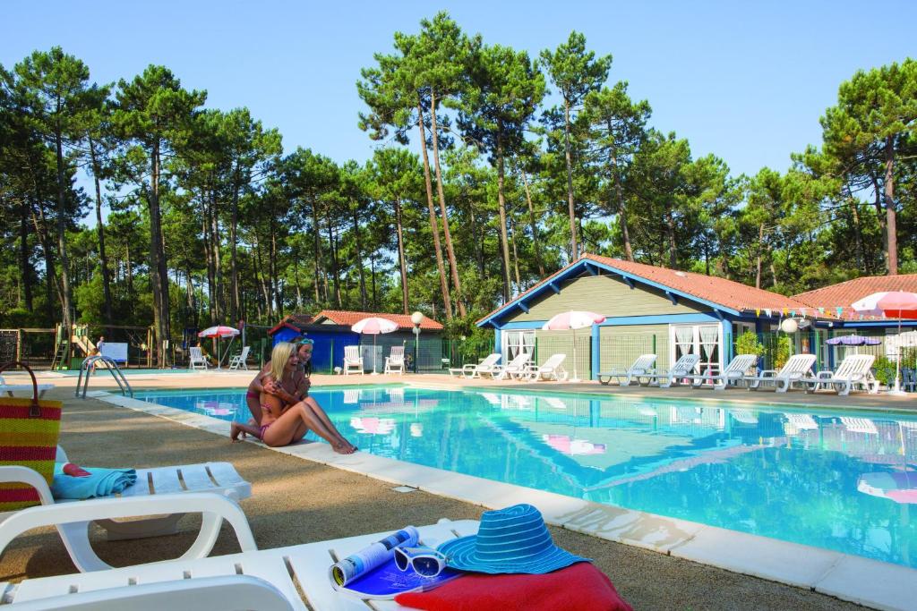 a woman sitting next to a swimming pool at VVF Landes Moliets in Moliets-et-Maa
