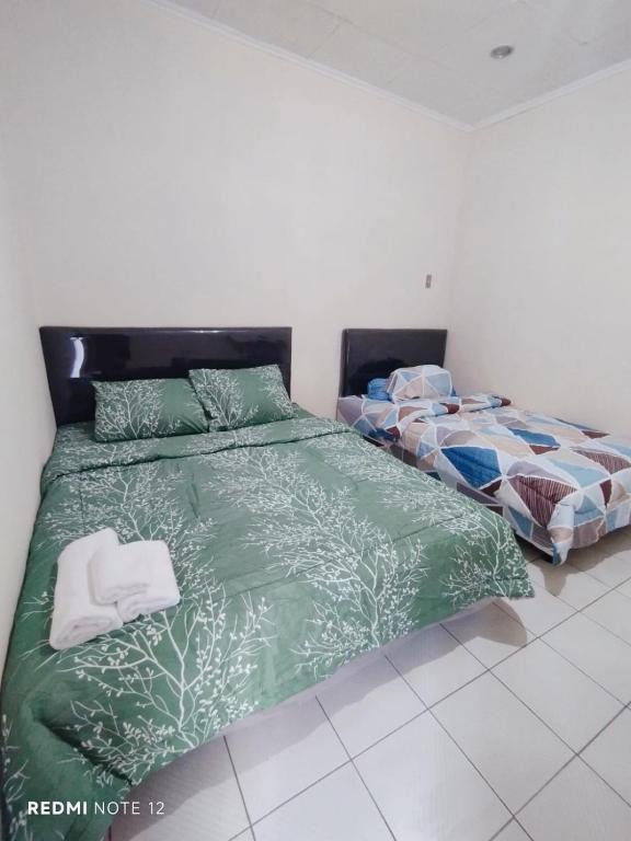 a bedroom with two beds with green comforter at Kos di Menteng, Jakarta Pusat in Jakarta