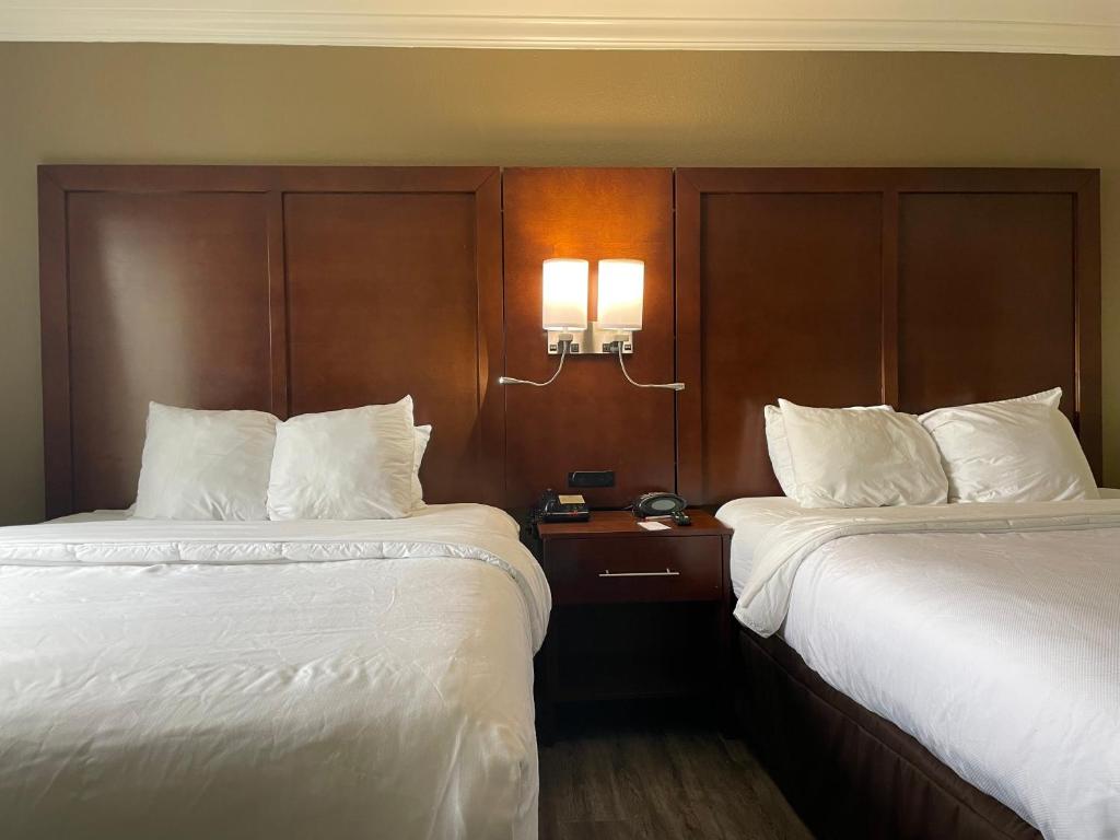 two beds in a hotel room with white sheets at Forestpark Suites in Cincinnati