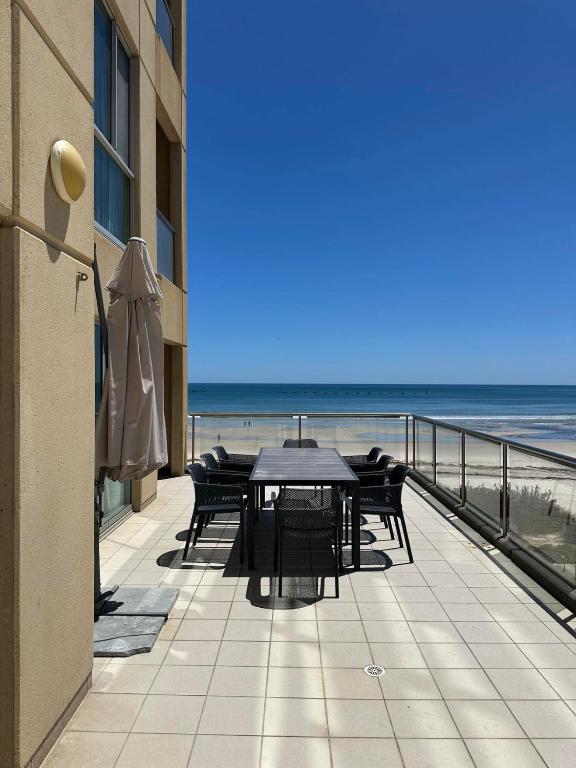 a table and chairs on a balcony overlooking the beach at Beachfront Serenity Glenelg in Glenelg