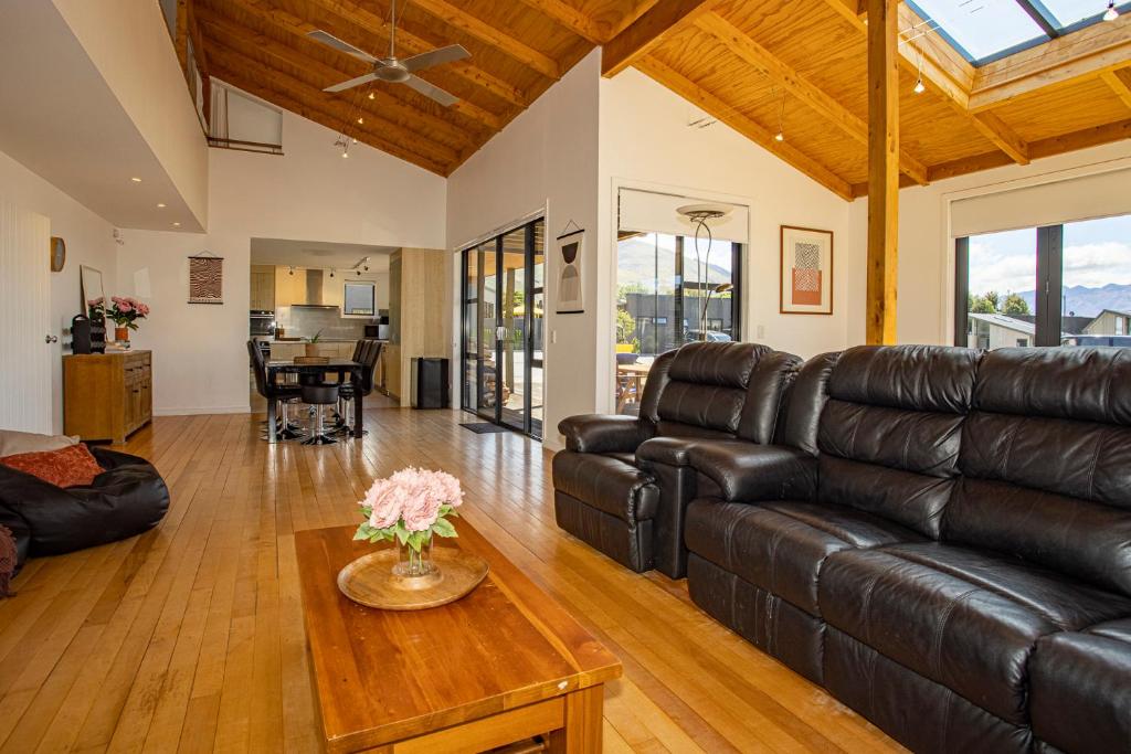 a living room with a leather couch and a table at Wanaka Retreat Spa, Sauna & Mountain Views in Wanaka