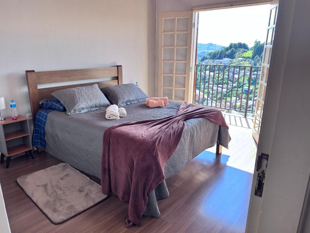 a bedroom with a bed and a large window at Casa Campos do Jordão in Campos do Jordão