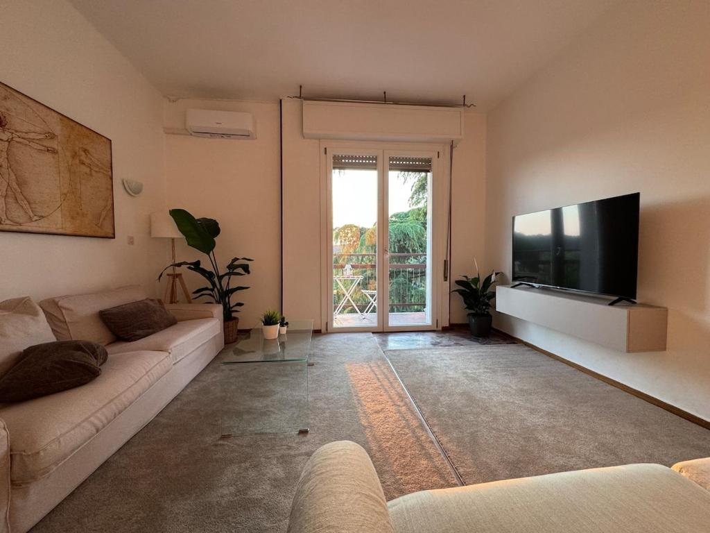 Una sala de estar con un sofá y un televisor de pantalla plana. en Cosy Penthouse near the hospital, en Brescia