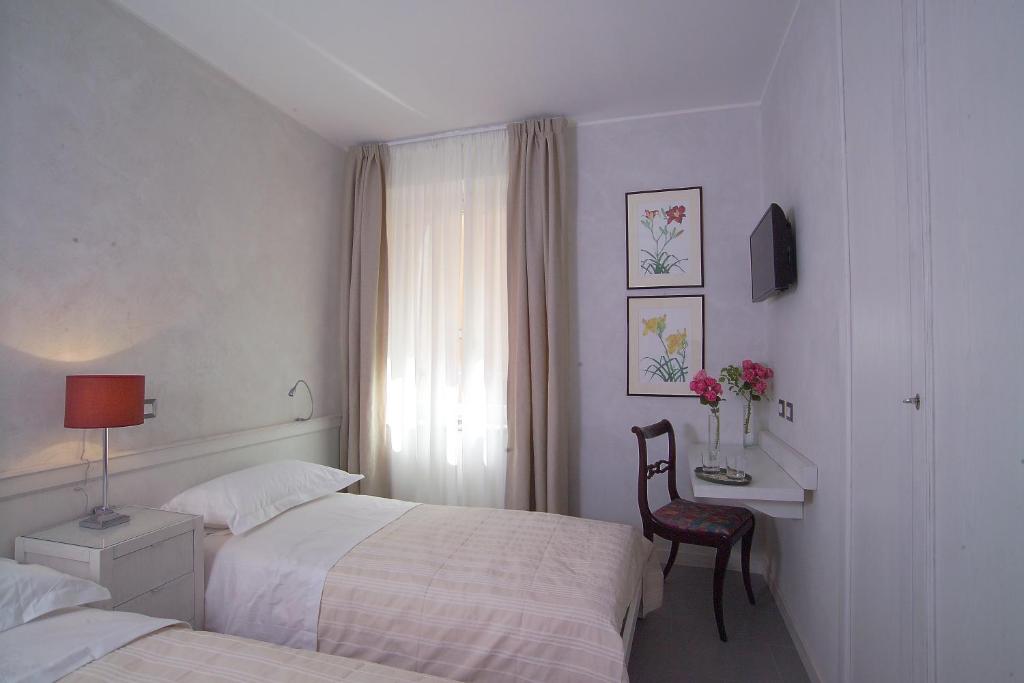 a bedroom with two beds and a desk and a window at Stazione di Posta San Gemini in San Gemini