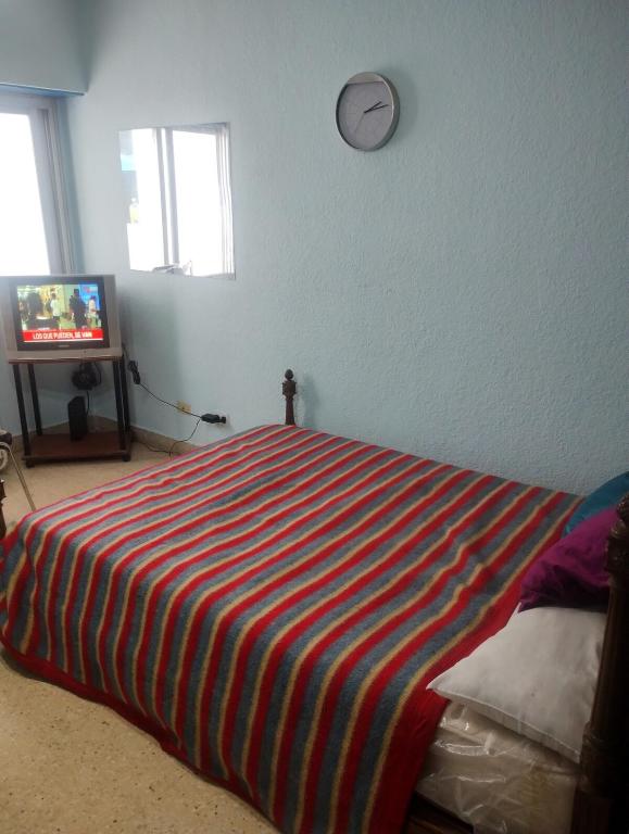 ein Schlafzimmer mit einem Bett mit einer gestreiften Decke in der Unterkunft Departamento zona microcentro in Mar del Plata