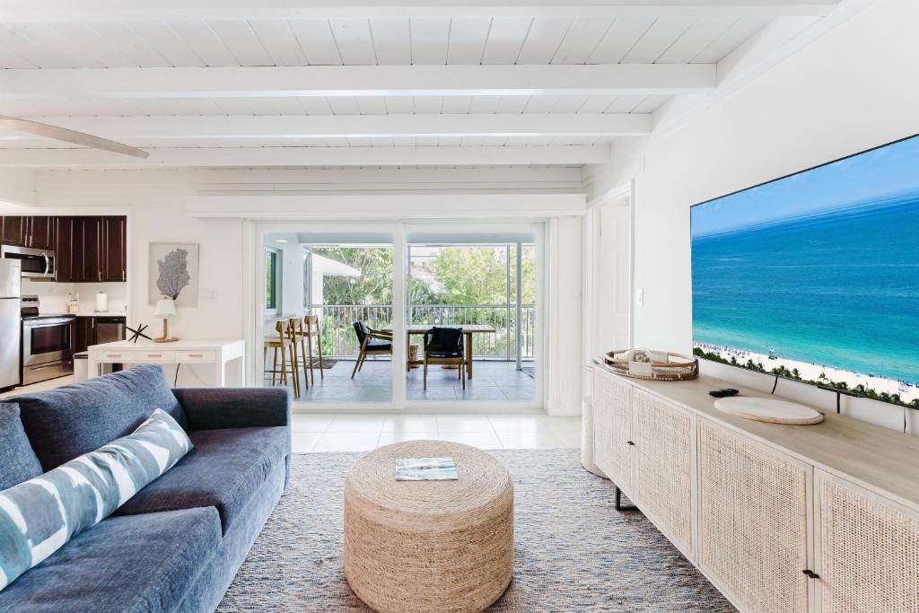 a living room with a blue couch and a large screen tv at Beachside 2BR 2BA - Pool & Balcony - Steps to Boca Beach in Boca Raton