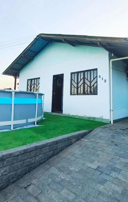 a white house with a black door and a yard at Casa térrea aconchegante in Blumenau