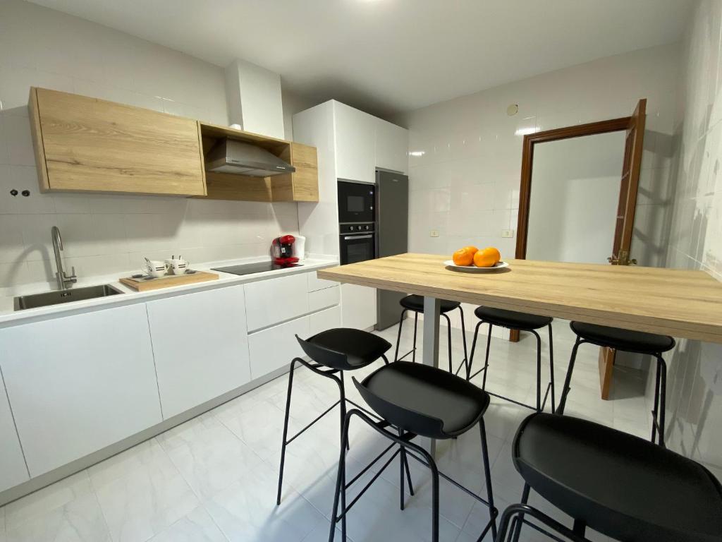 a kitchen with white cabinets and a wooden counter with stools at A dos Pasos in Caldas de Reis