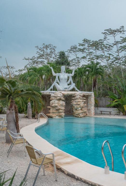a swimming pool with a fountain and chairs next to it at Kasa UhMay Tulum in Francisco Uh May