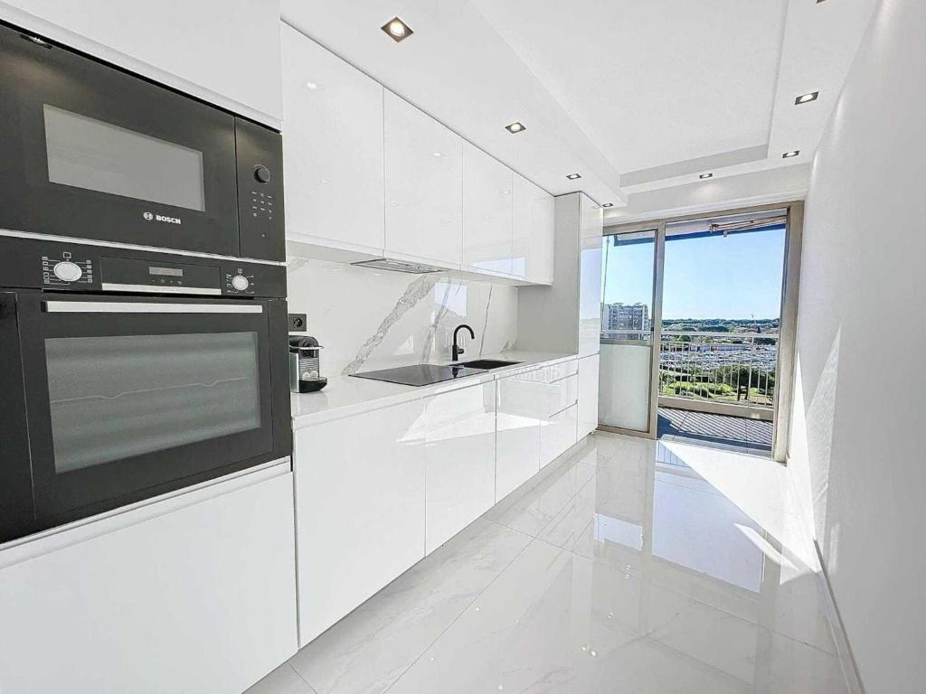 une cuisine blanche avec un évier et une cuisinière dans l'établissement Modern apartment - AC-1BR- 4P - Mandelieu, à Mandelieu-la-Napoule