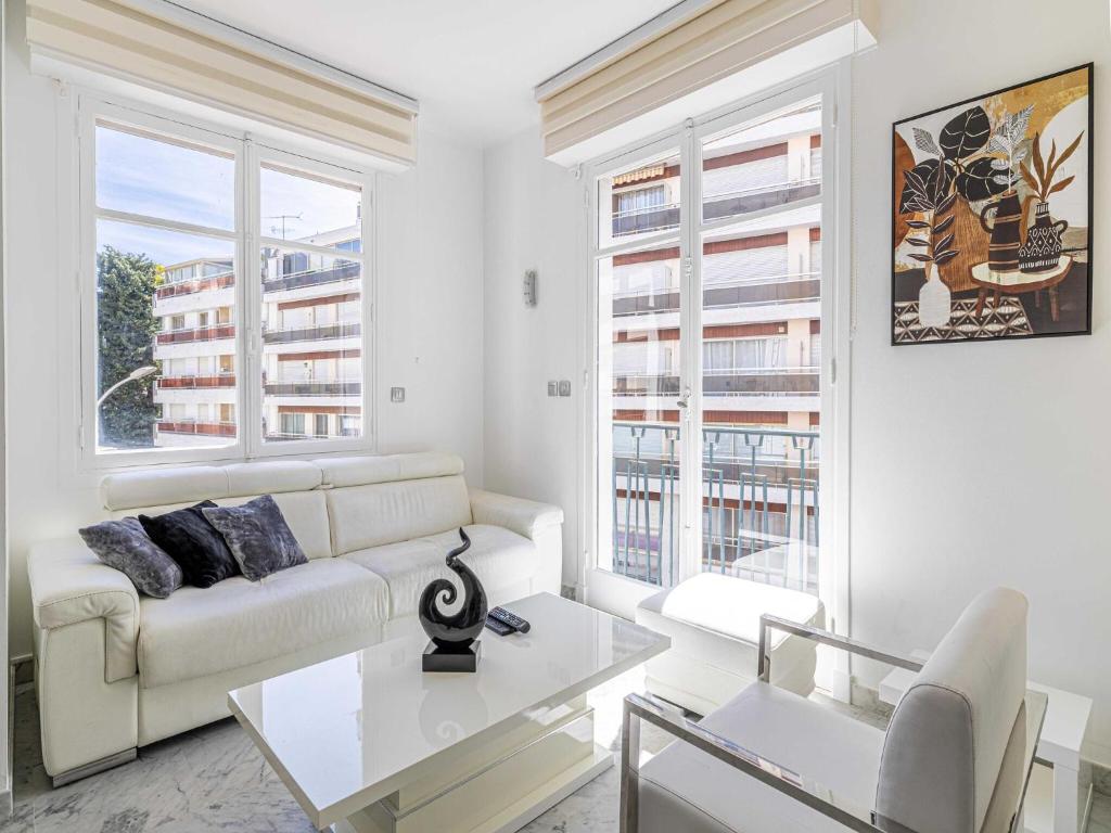 - un salon blanc avec un canapé et 2 fenêtres dans l'établissement Modern apartment - 2BR-4P- Croisette plage, à Cannes