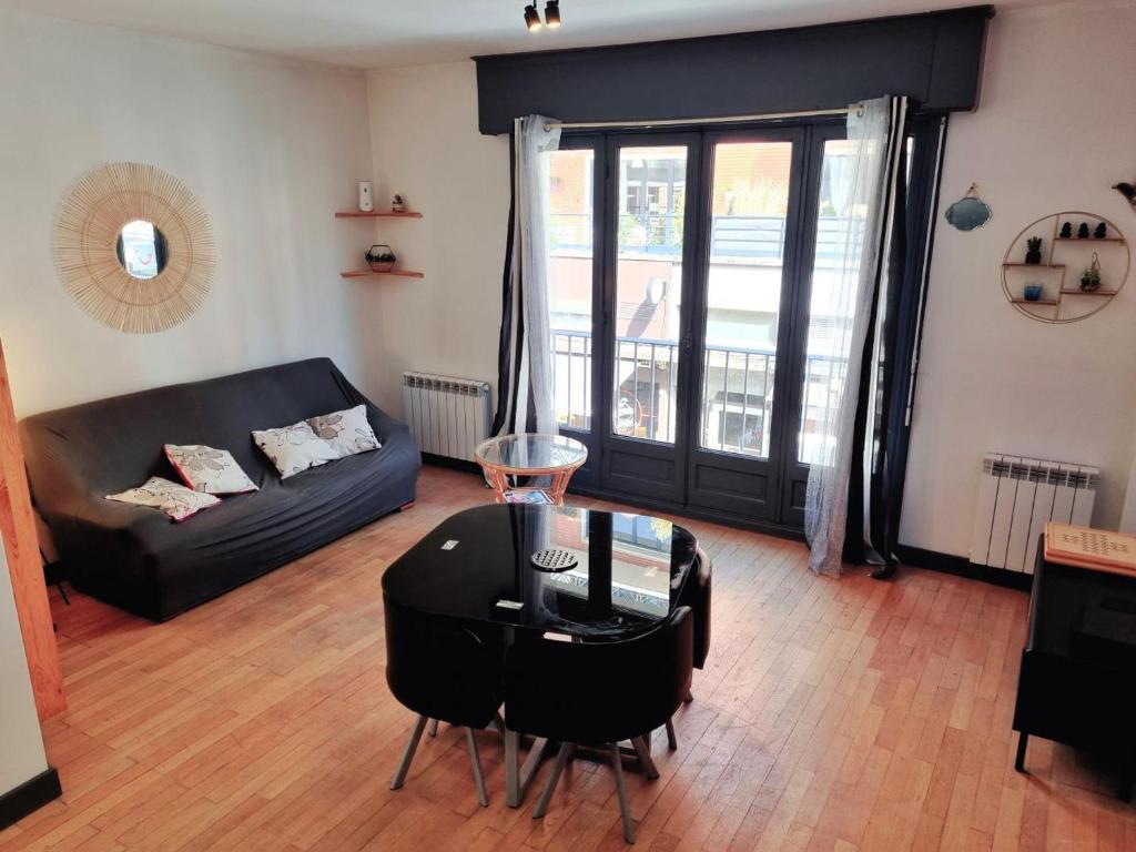 a living room with a black couch and a glass table at Duplex en Centre-Ville de Valenciennes Tout Inclus - FR-1-510-232 in Valenciennes