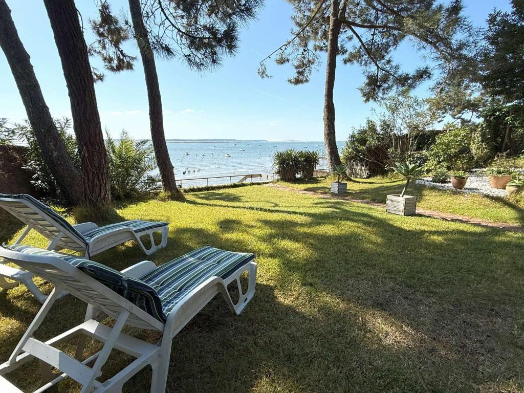 deux chaises blanches assises sur l'herbe près de l'eau dans l'établissement Villa au bord du bassin, jardin privé, WIFI, parking, 8 pers. - FR-1-736-61, à Lège-Cap-Ferret