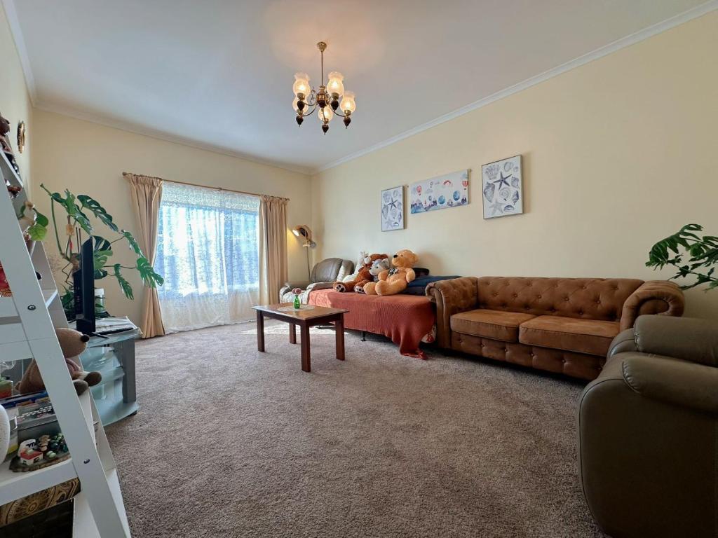 a living room with a couch with a teddy bear on it at Coleman Comfort Hub - close to City&Air port in Moonah