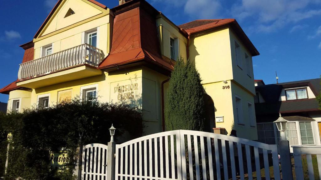 マリアーンスケー・ラーズニェにあるPension Elbrsの白い柵の黄色い家