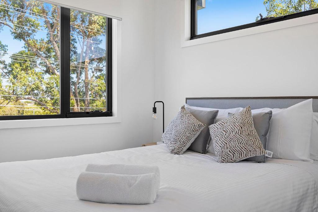 a white bedroom with a white bed with windows at Domi Rentals - The Moorabbin Townhouse in Moorabbin