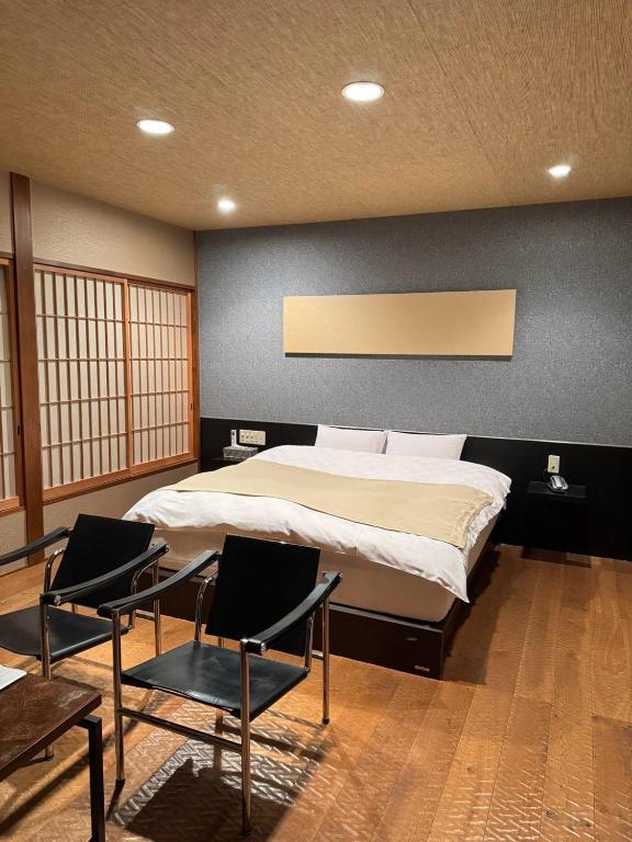 Saijō-chōにあるHotel JOYCEの大きなベッドと椅子2脚のある寝室