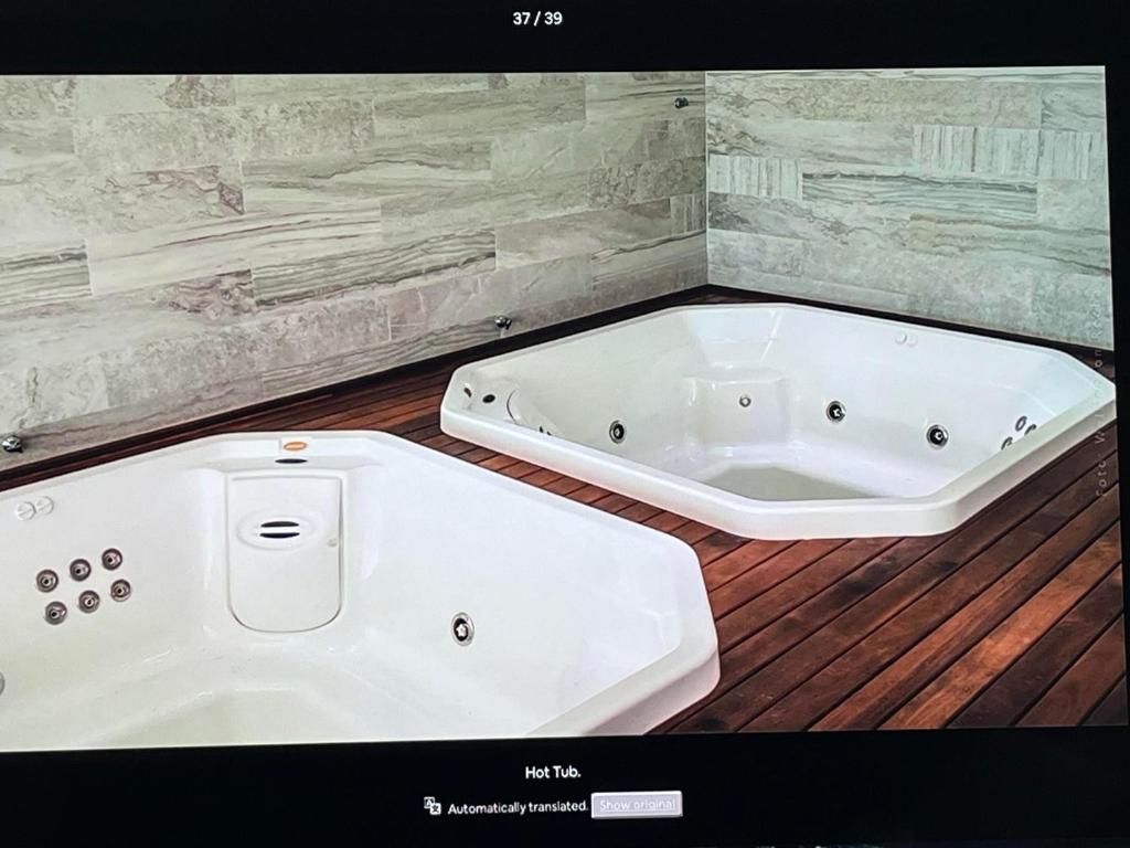 a white bath tub in a room with a wooden floor at Lindo Por Do Sol in Arraial do Cabo